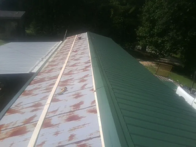 Old rusted panels beside newly installed green metal roofing — Wind Damage Roof Repair by Roofing Brothers in Mansfield