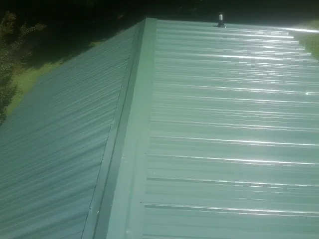 New green metal panels meeting at the ridge of a roof — Flat Roof Repair work by our crew in Mansfield